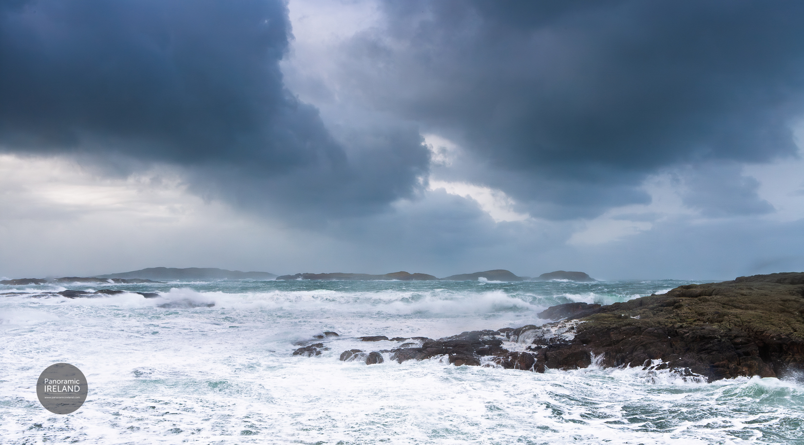 Stormy, turbulent Atlantic Ocean on Ireland's west coast. A wild and energetic scene of clouds and waves, the ocean almost pure white with wave activity. Rocks and offshore islands are battered by waves.