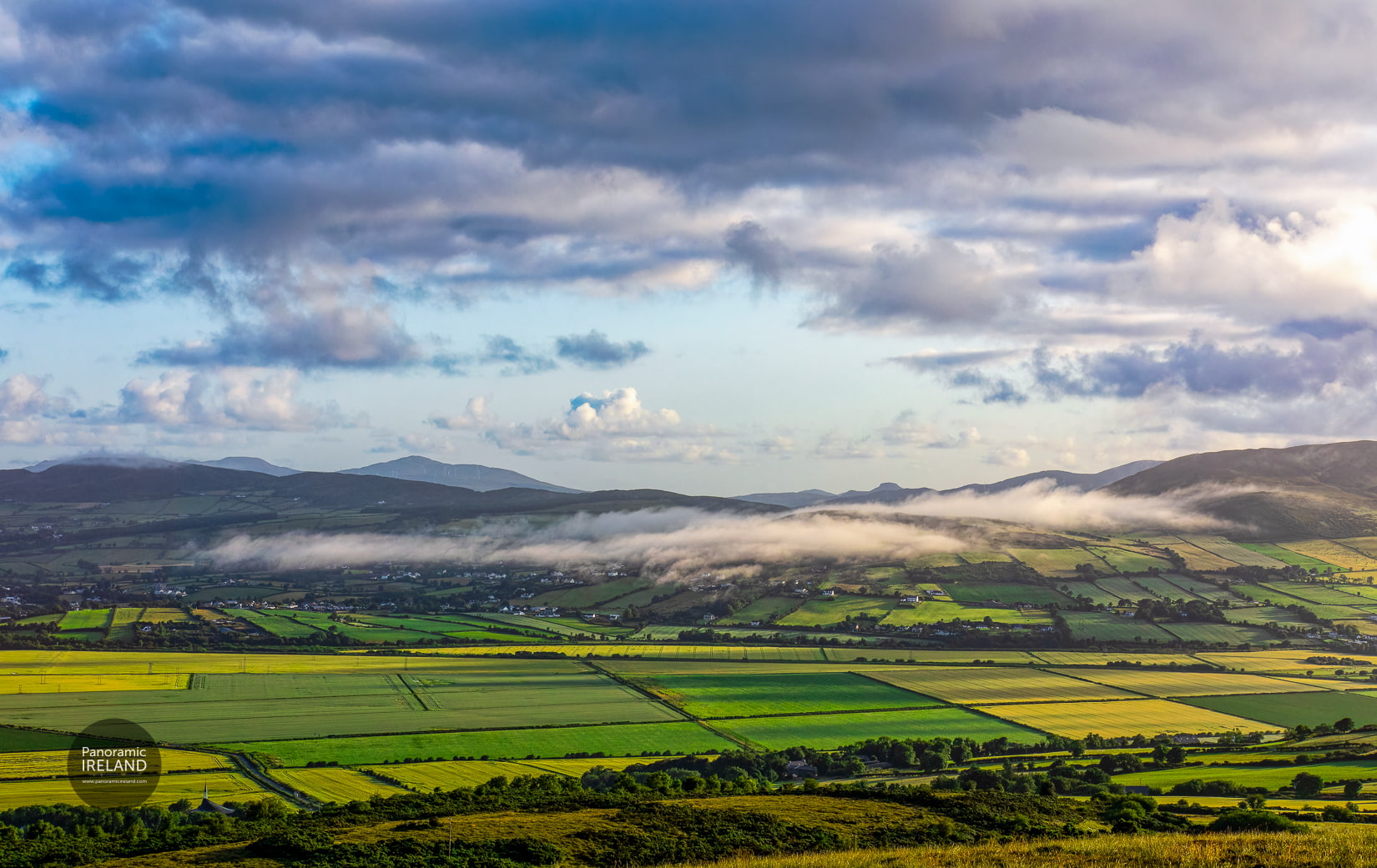 A landscape of green fields and wisping clouds in Donegal, Ireland