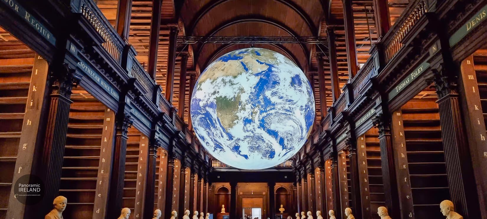 Luke Jerram’s Gaia illuminated Earth sculpture hanging in the Long Room Library, Trinity College Dublin, with partly emptied book shelves during the conservation project