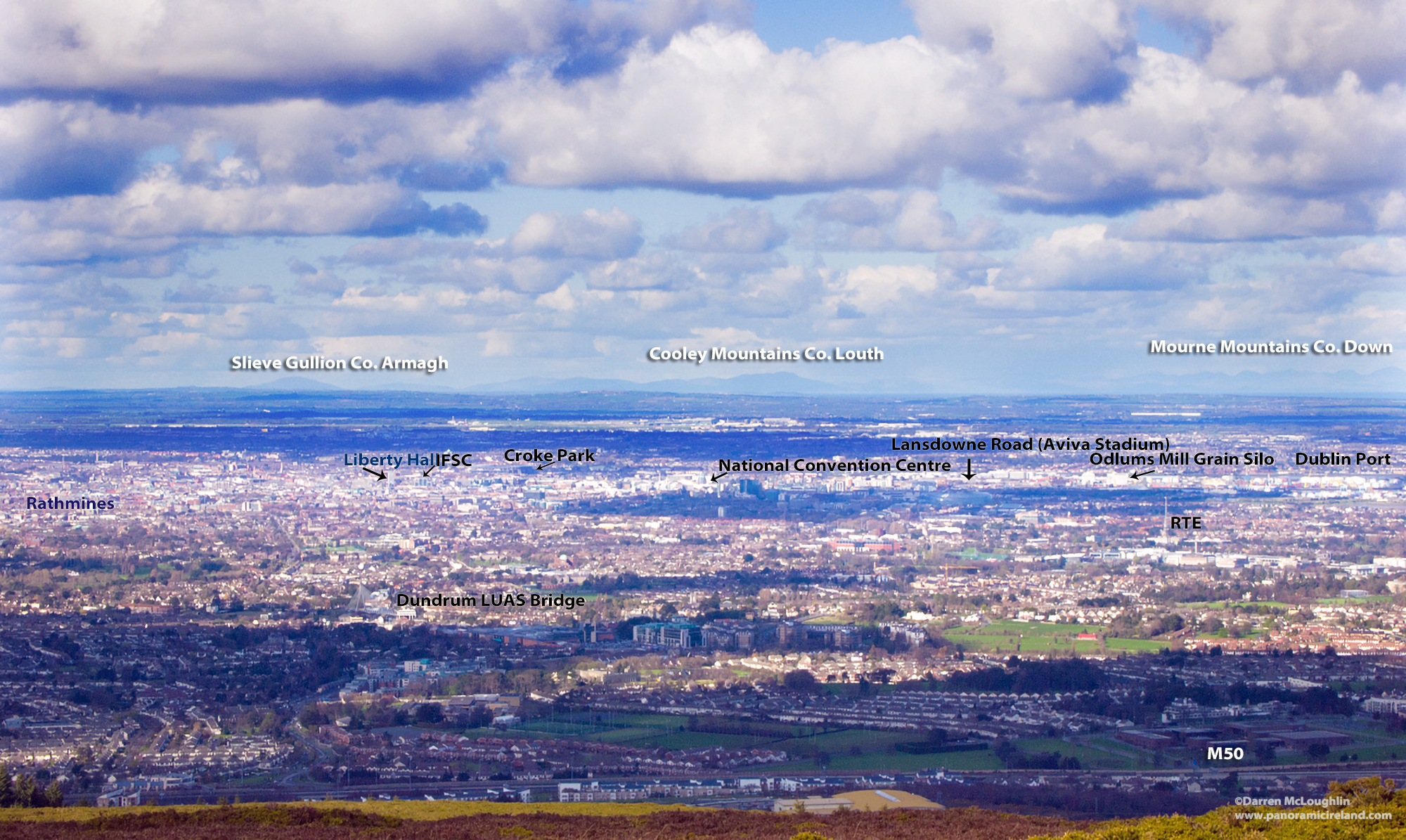 View over Dublin from the mountains, looking north across the city to distant mountains beyond and showing locations of some of the city's main sights.